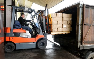 Electric forklift in warehouse loading cardboard boxes